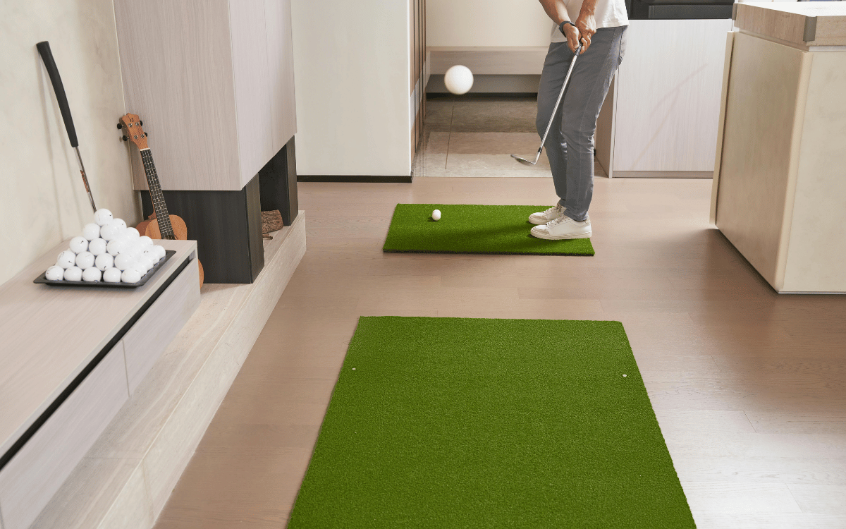 Hombre jugando al golf en jardín privado con instalación de empresa de césped artificial en Sabadell