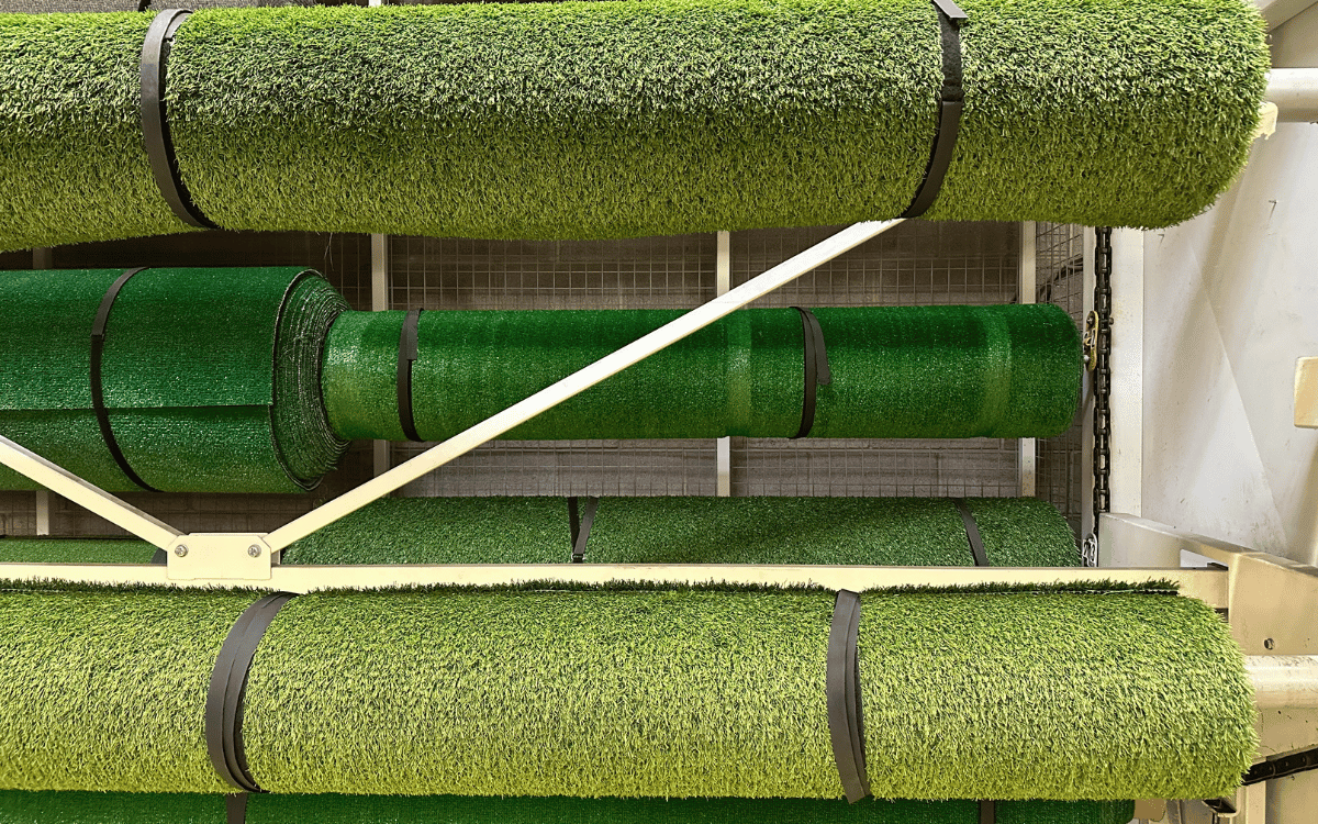 Rollos de césped artificial verde listo para extender sobre superficie preparada